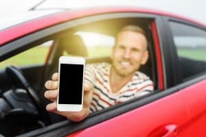Man in car showing smart phone.